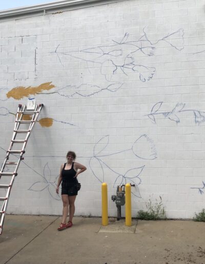 Artist Dania and her outlines for a mural on the Pharmhouse grow building.